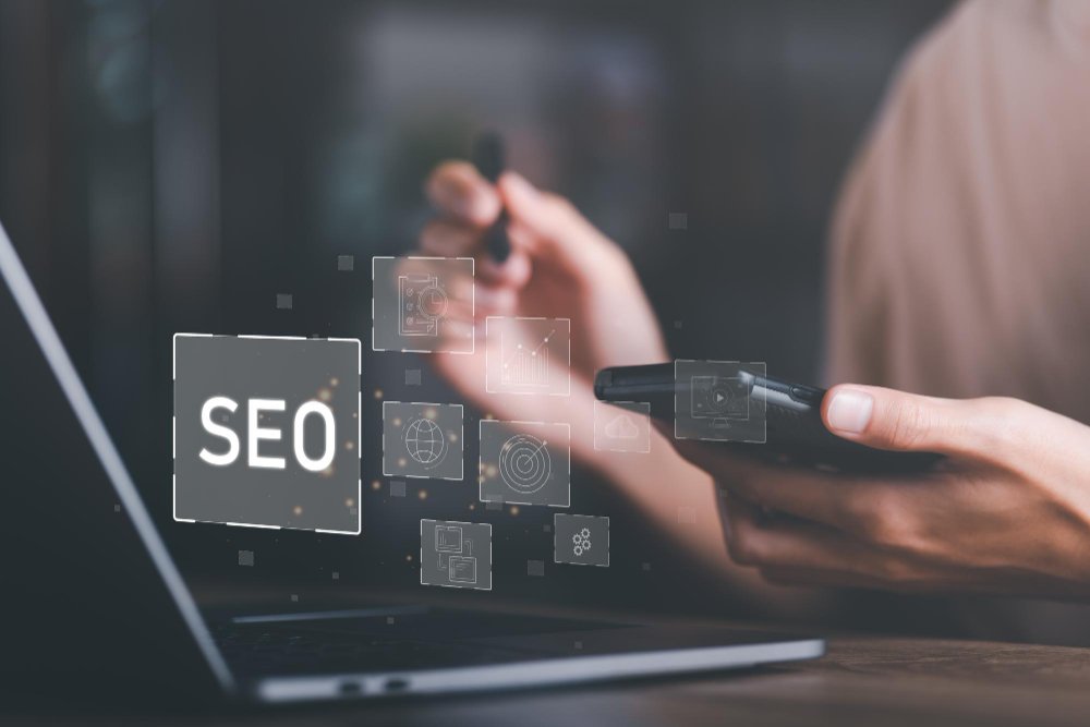 Agência de SEO: Mãos de uma pessoa digitando no teclado de um laptop, com a palavra “SEO” exibida na tela.