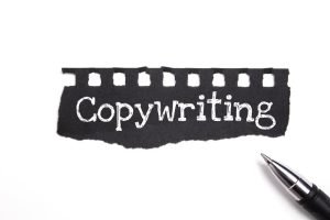 Copywriting criativo: Uma imagem em preto e branco mostrando a palavra "Copywriting" escrita em um pedaço de papel rasgado. e uma caneta ao lado