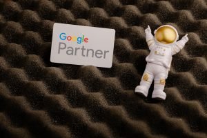 Agência Google Partner: Uma placa branca do Google Partner e uma pequena figura de astronauta branca em um fundo texturizado marrom.